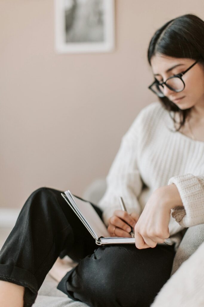 woman writing with a pen in a journal