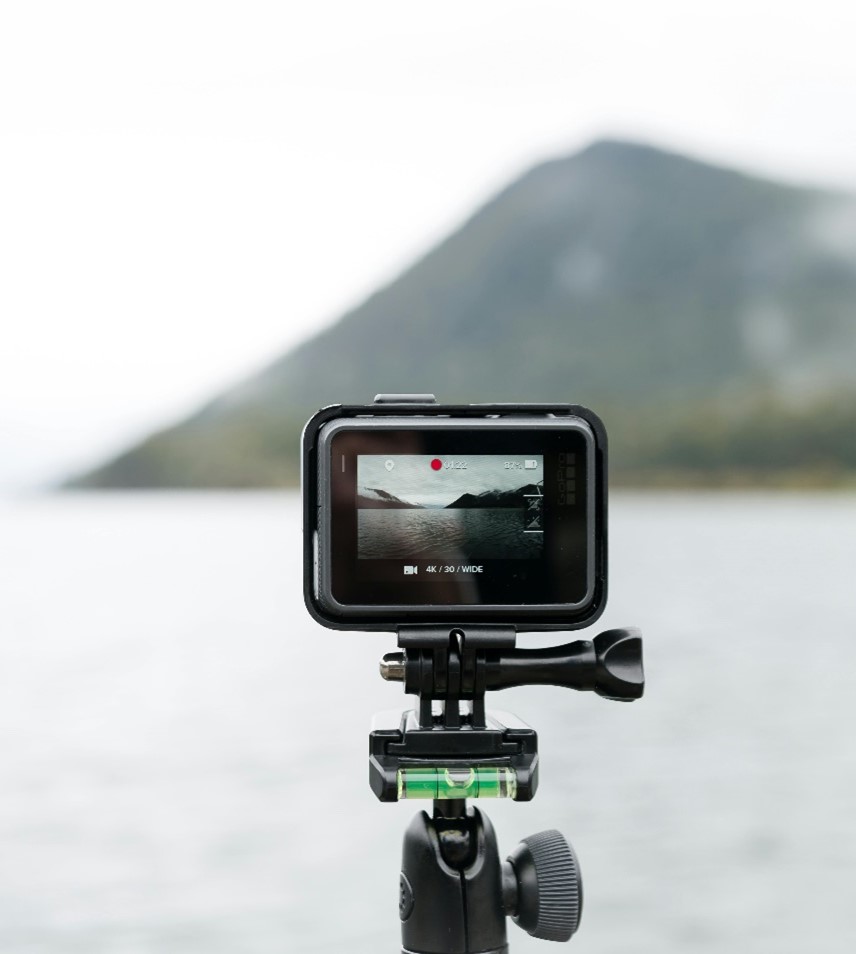 Video camera showing mountain and ocean scene on its screen with the blurred scene in the background